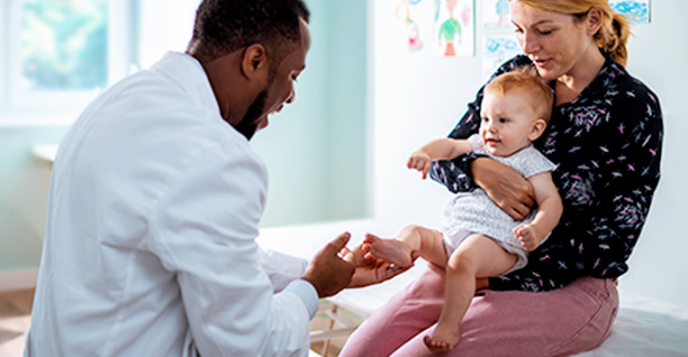 Pediatrician examines child with mother nearby