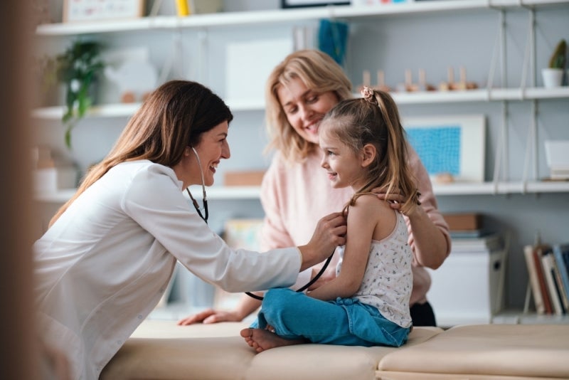 Doctor examing child patient with parent watching