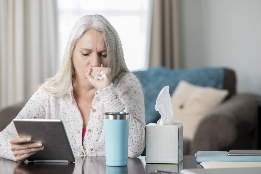 older woman sick checking tablet